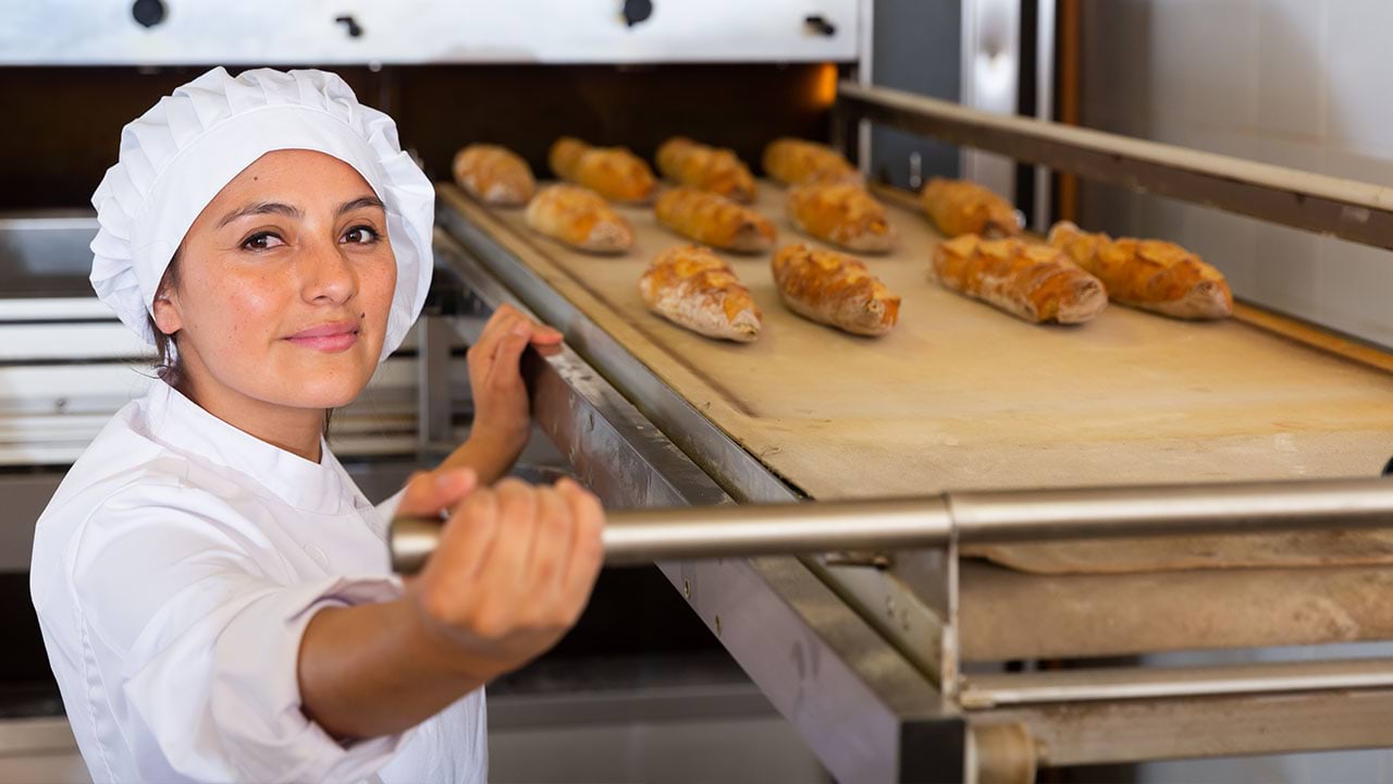 Baker taking pastries out of industrial oven 