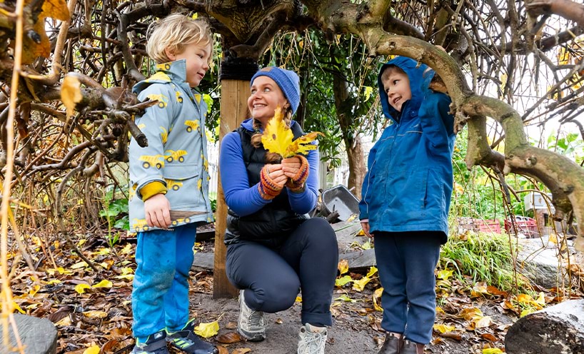 Children and their educator under a tree.