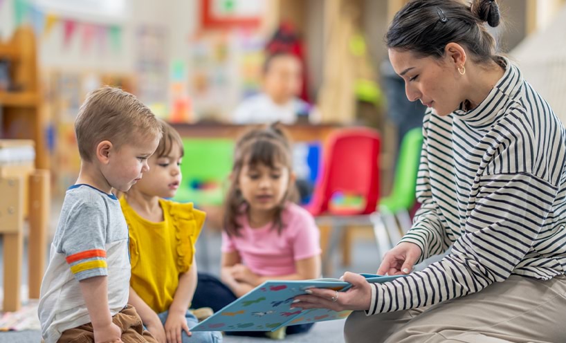 Educator reading a book to children.