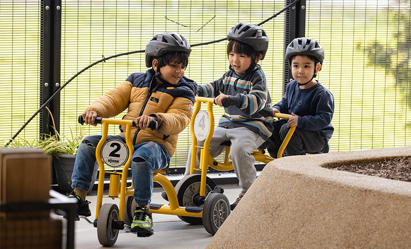 3 small children riding yellow tricycles.