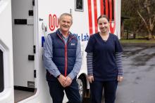 Two people standing in front of a white mobile skills lab