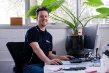 Adam Bignold sitting at his desk and smiling