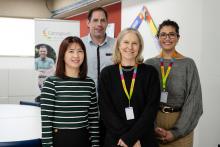 Four staff smiling and standing in an office