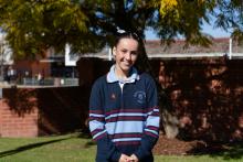 Person standing in front of a school smiling