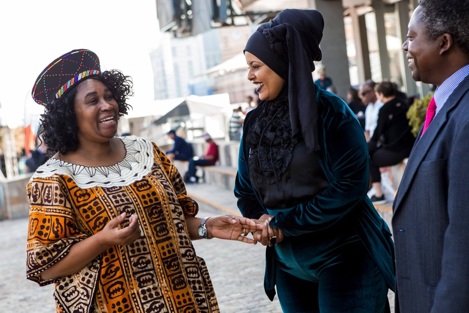 Three people of African background speaking to each other.