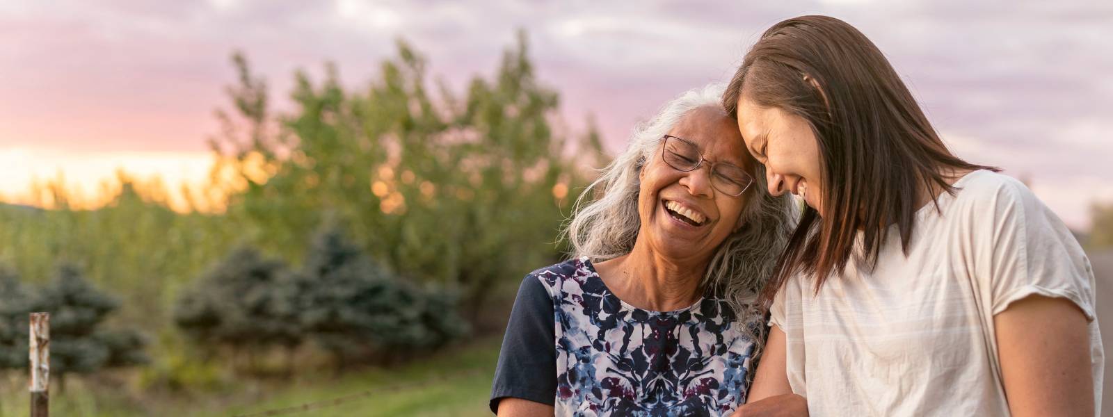 Two smiling women with heads bent towards each other