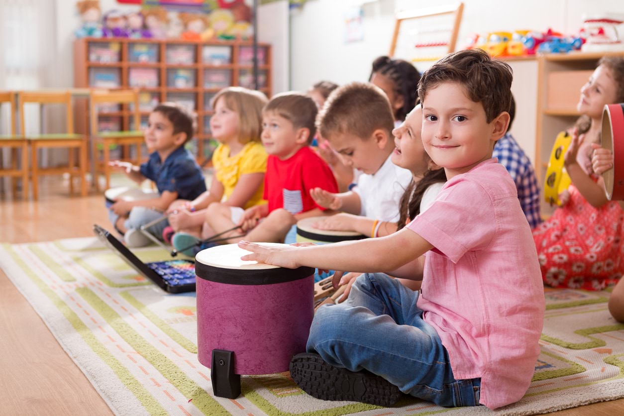 Young children sitting on the floor playing musical instruments.