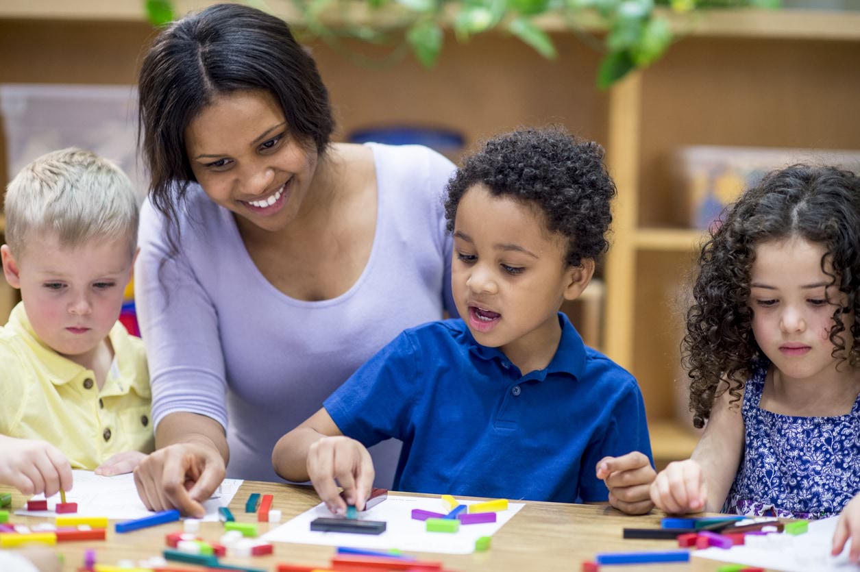 Young children playing with blocks with a teacher.