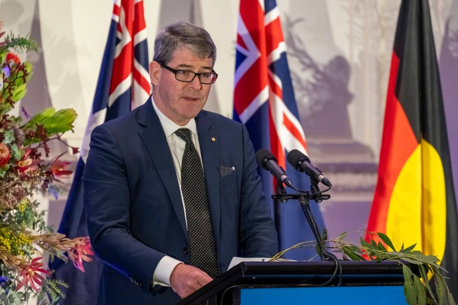 A man stands at a podium speaking into a microphone. 