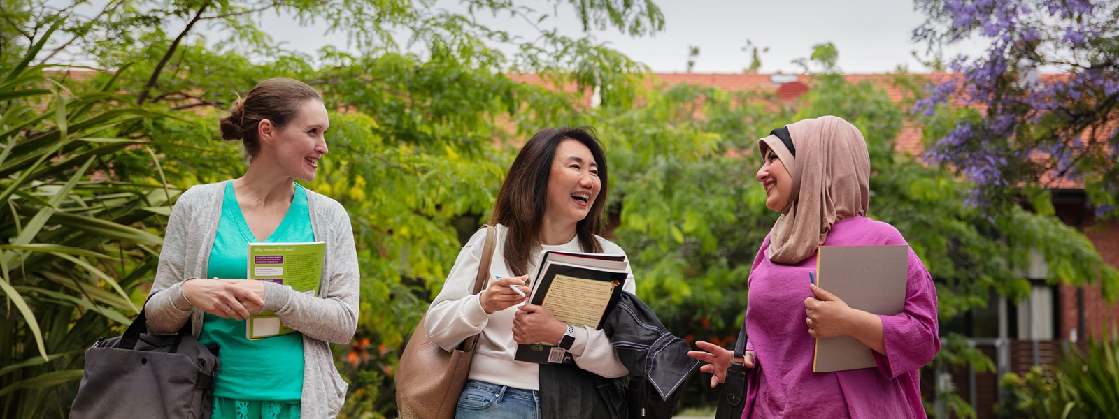 Three students walking next to each other outside, smiling. 