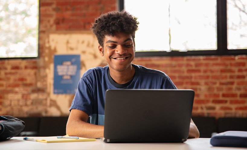 A student looking at a laptop and smling.