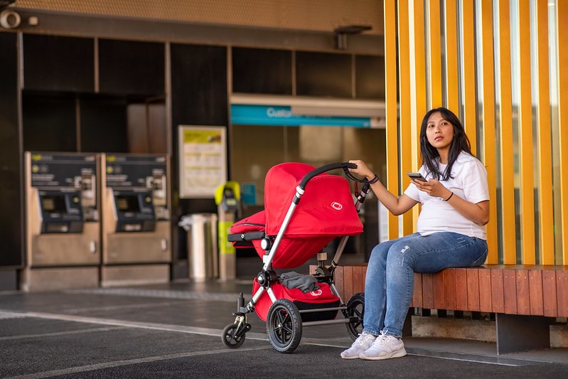 A person sitting on a bench with a stroller