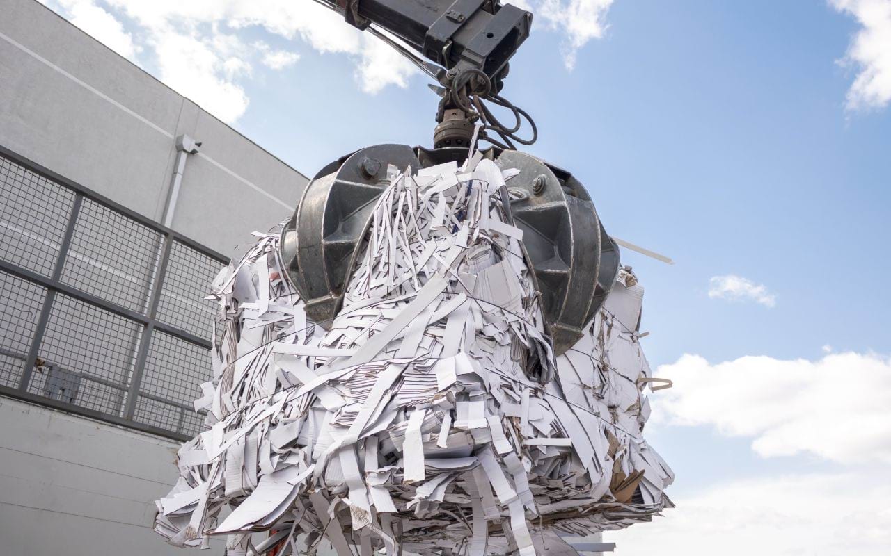 A crane picking up a bale of paper and cardboard for recycling