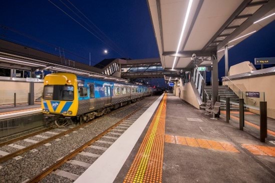 Photo of the new Bonbeach train station, showing a train coming to a stop and the tactile group surface indicators