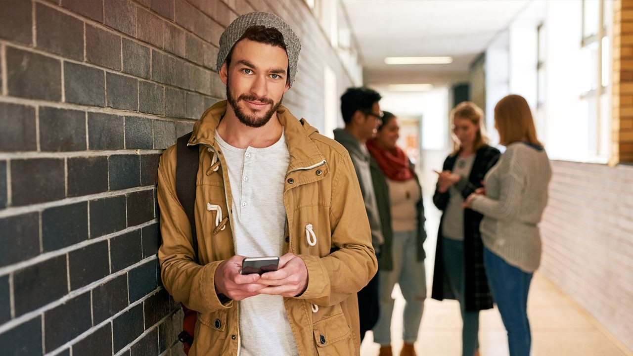 Student standing in hallway, looking at phone