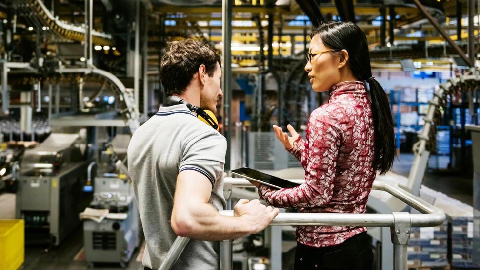 Female engineer and male mechanic talking in factory