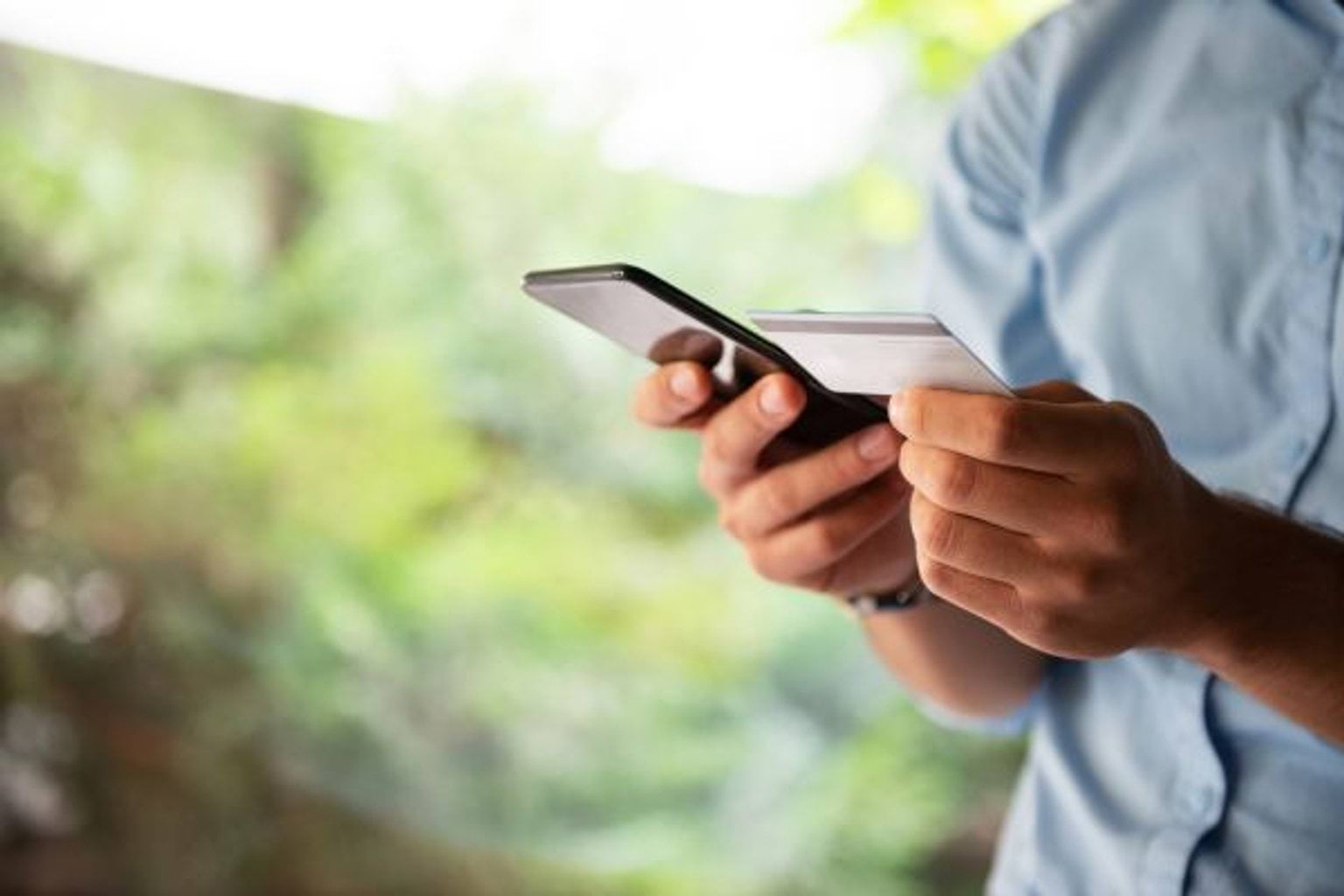 person holding a phone in right hand and credit card in left hand