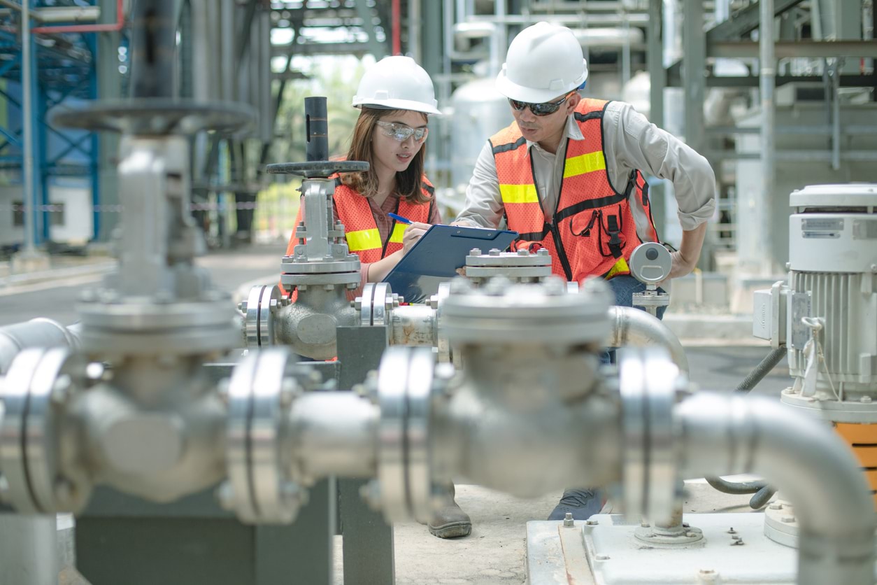 Female and male engineers inspecting machinery