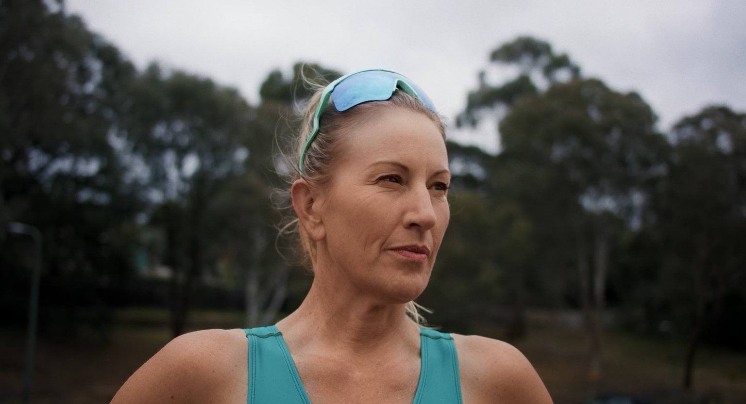 A woman wearing sunglasses and a green tank top.
