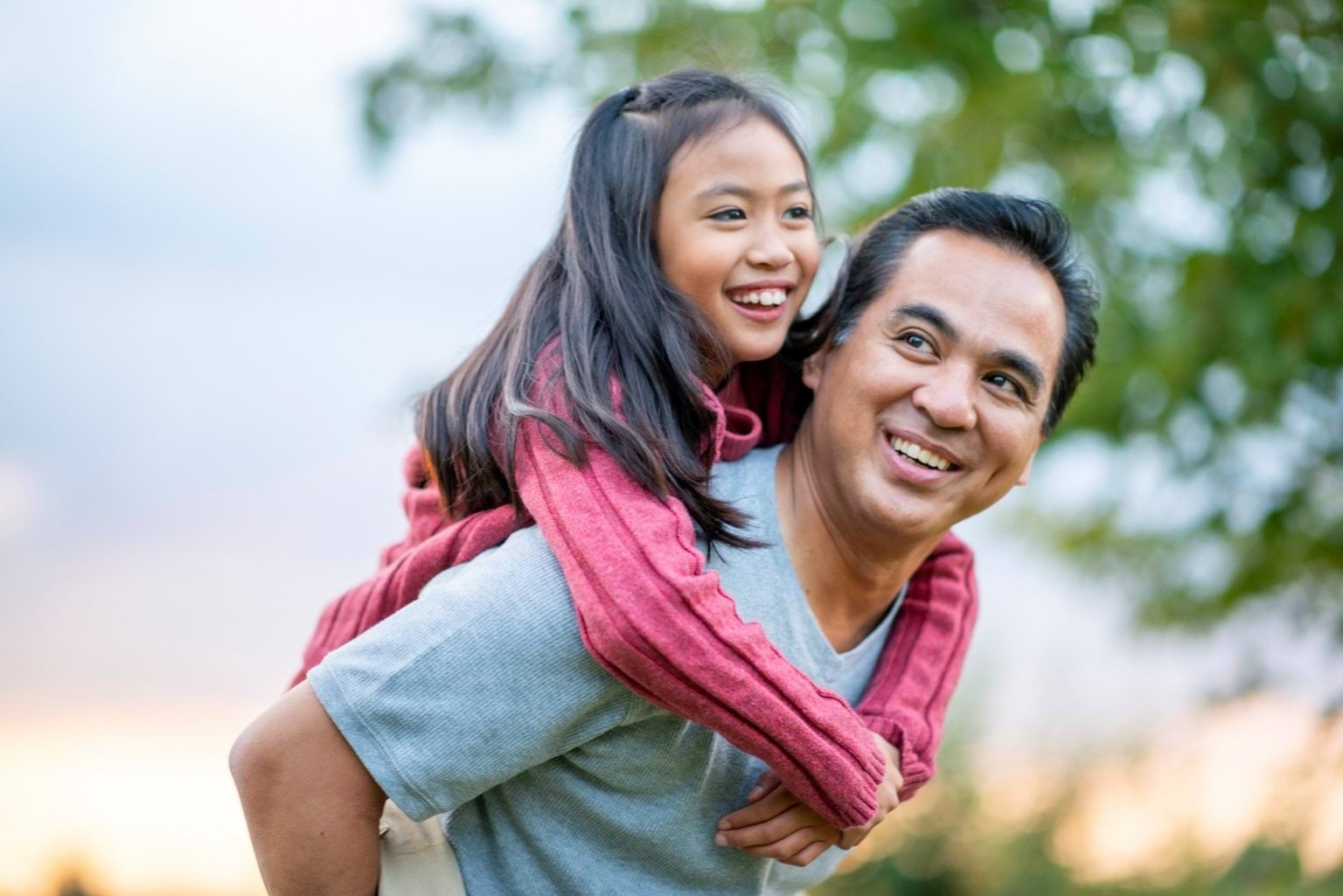 A man giving a young girl a piggyback ride.
