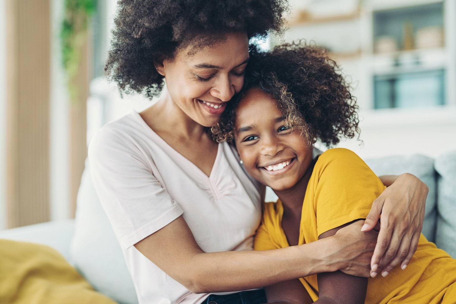 A woman and teenage girl sitting on the couch together.