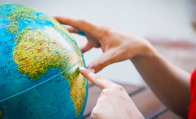 Two hands exploring the globe