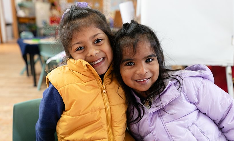 Two children smiling and leaning upon each other