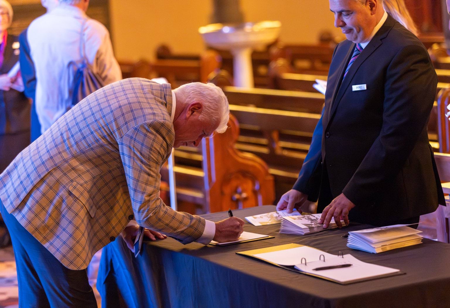 Attendee signing a condolence book at the State Funeral Service for Neale Fraser AO MBE