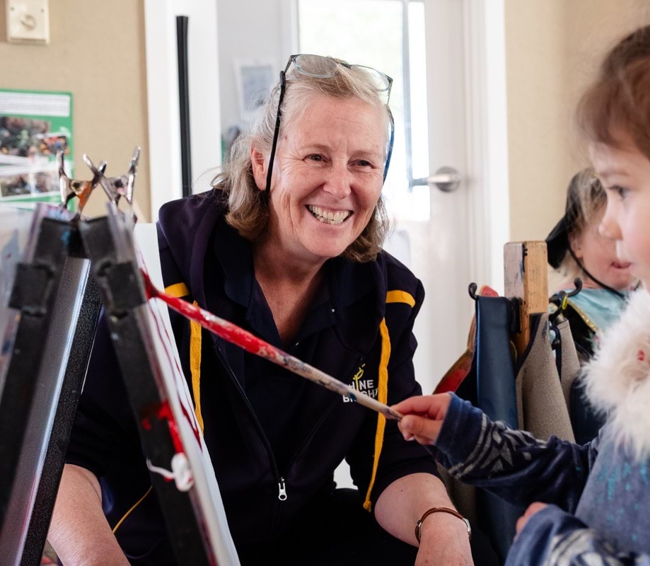 Sandra Houlahan encouraging a child to paint.