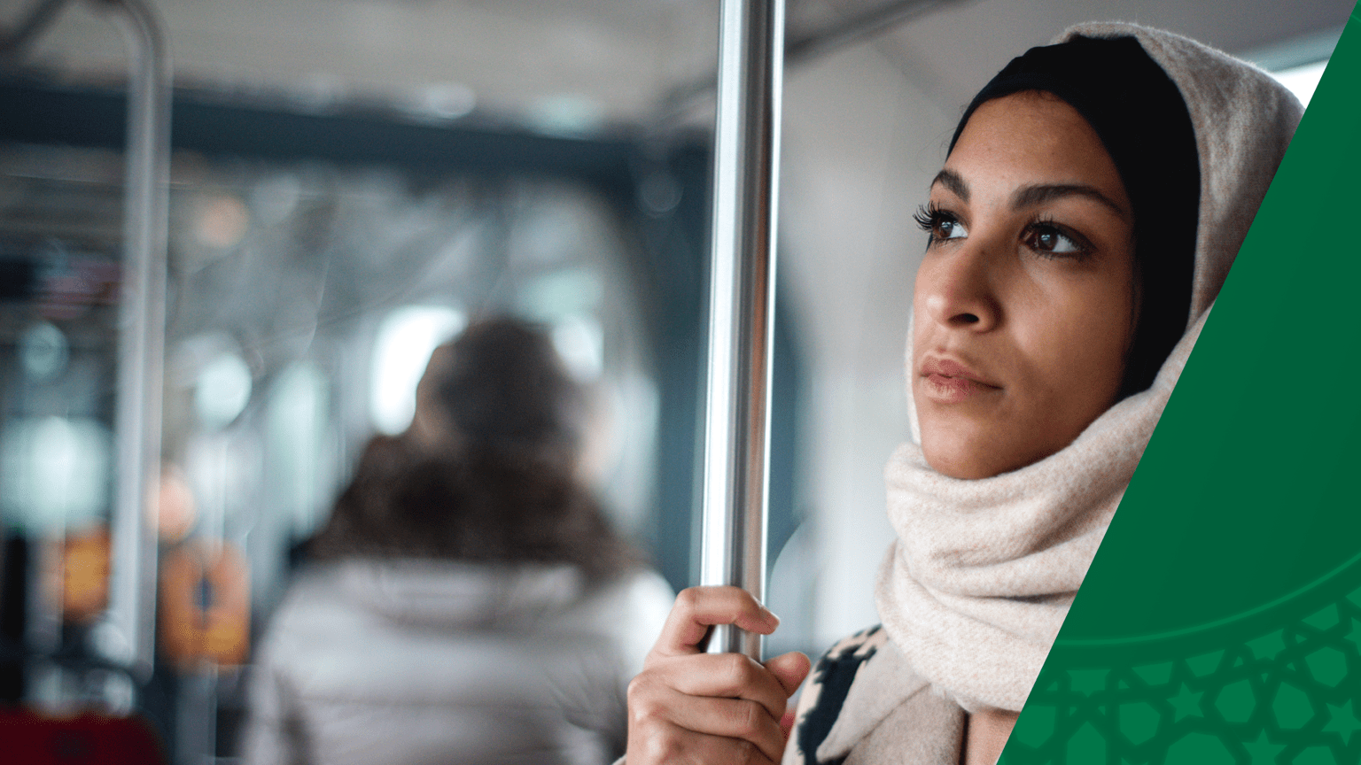 A women in a hijab is standing inside a bus, looking out the window