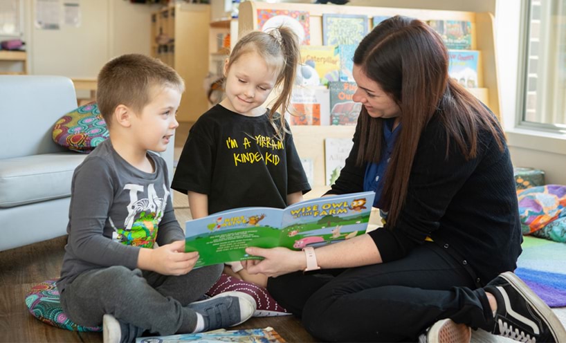 An educator reading a book to two children