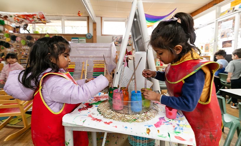 Two children painting on a canvas each