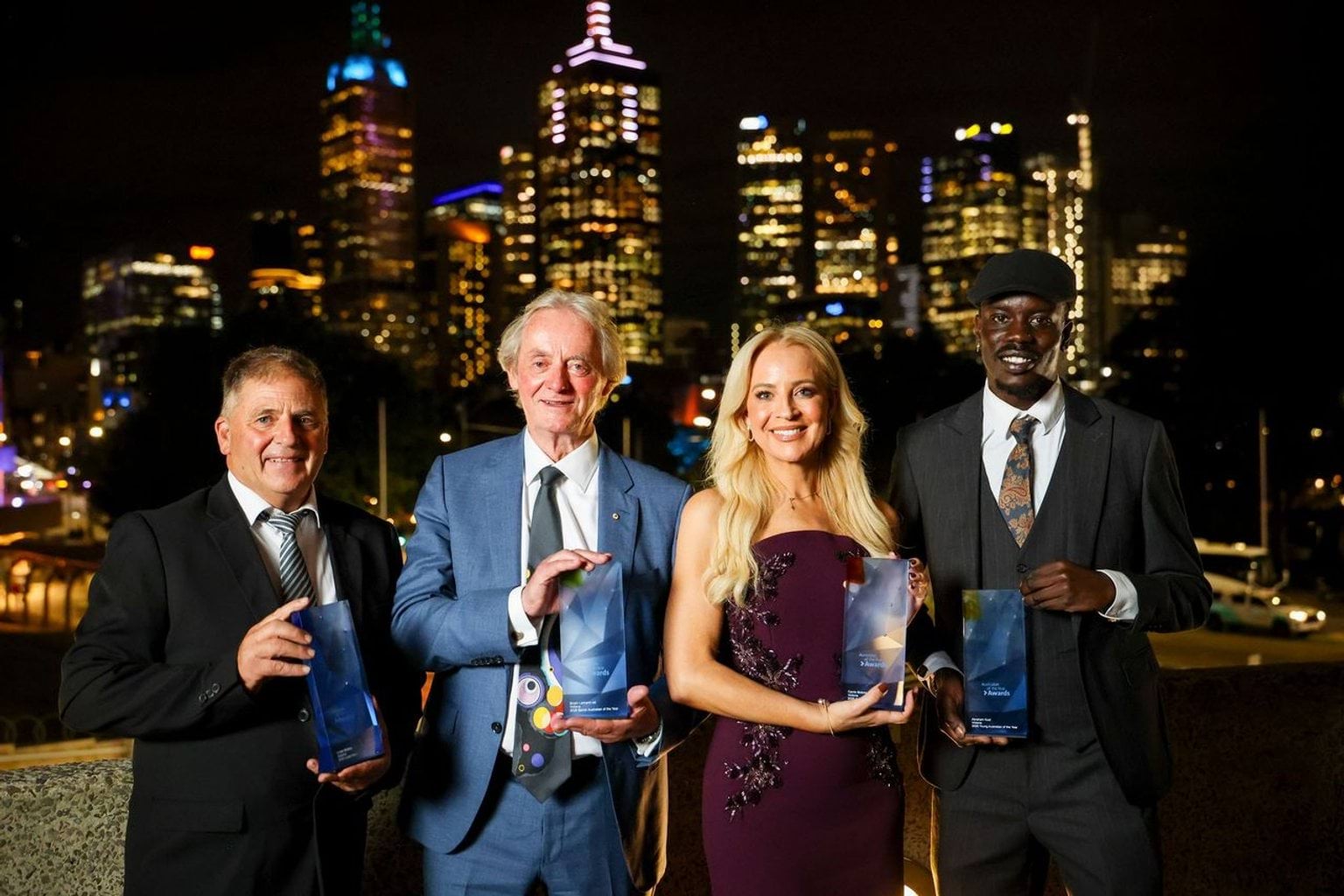Image of four Victorian recipients holding trophies with Melbourne skyline