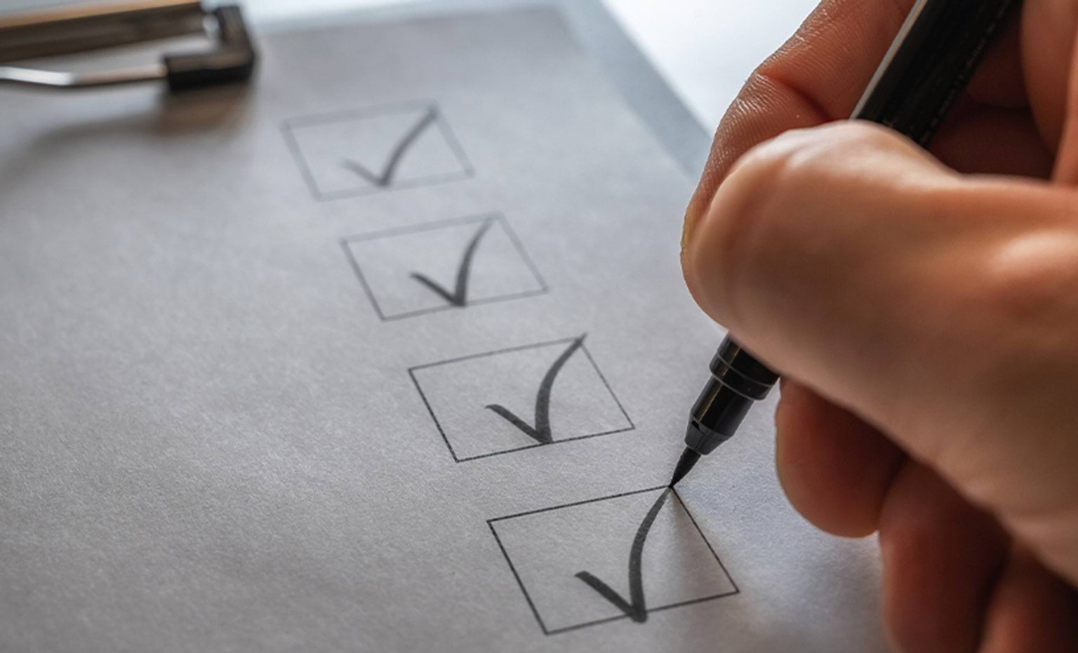 A checklist on a clipboard being ticked off