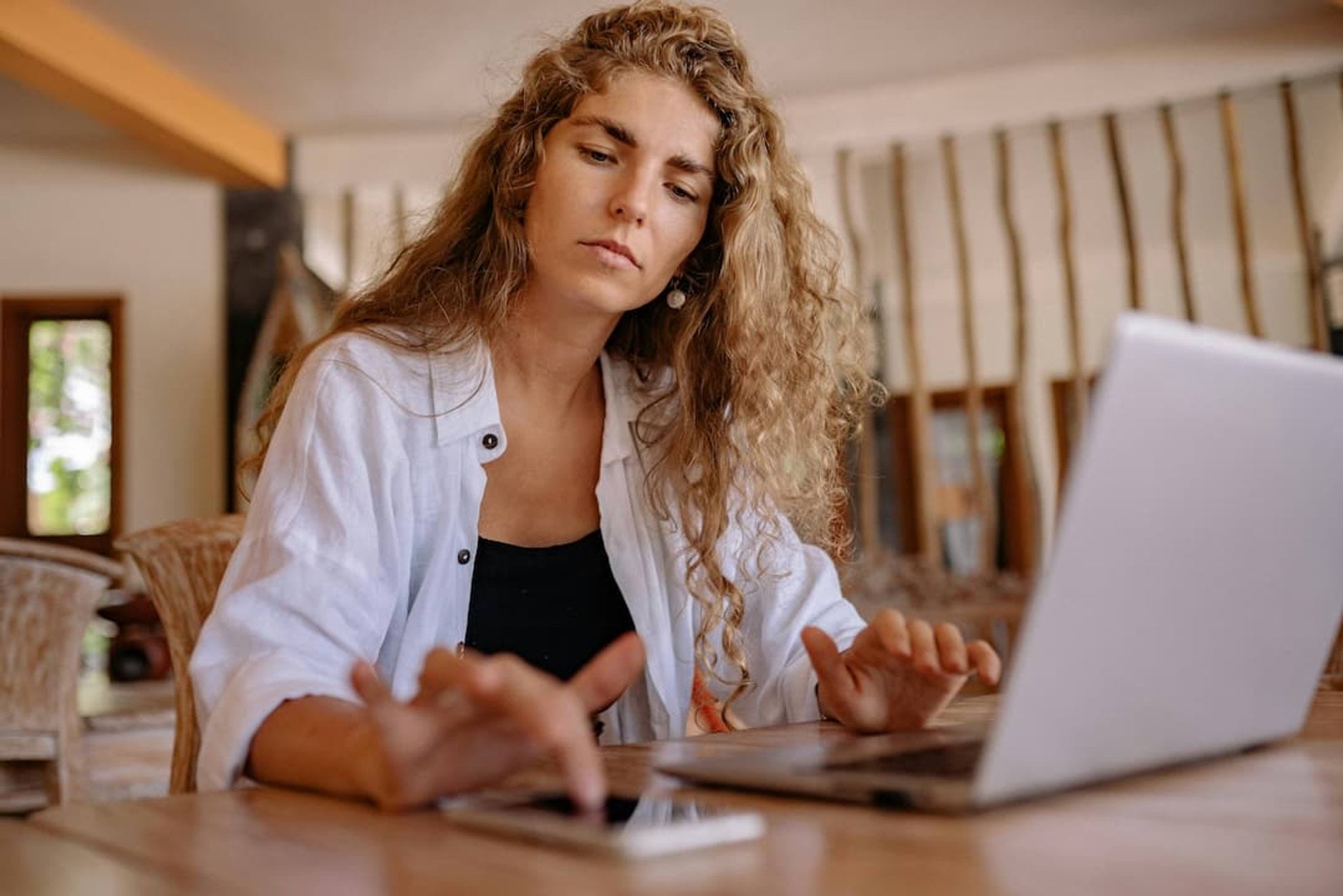 Woman sitting at table with laptop and mobile phone