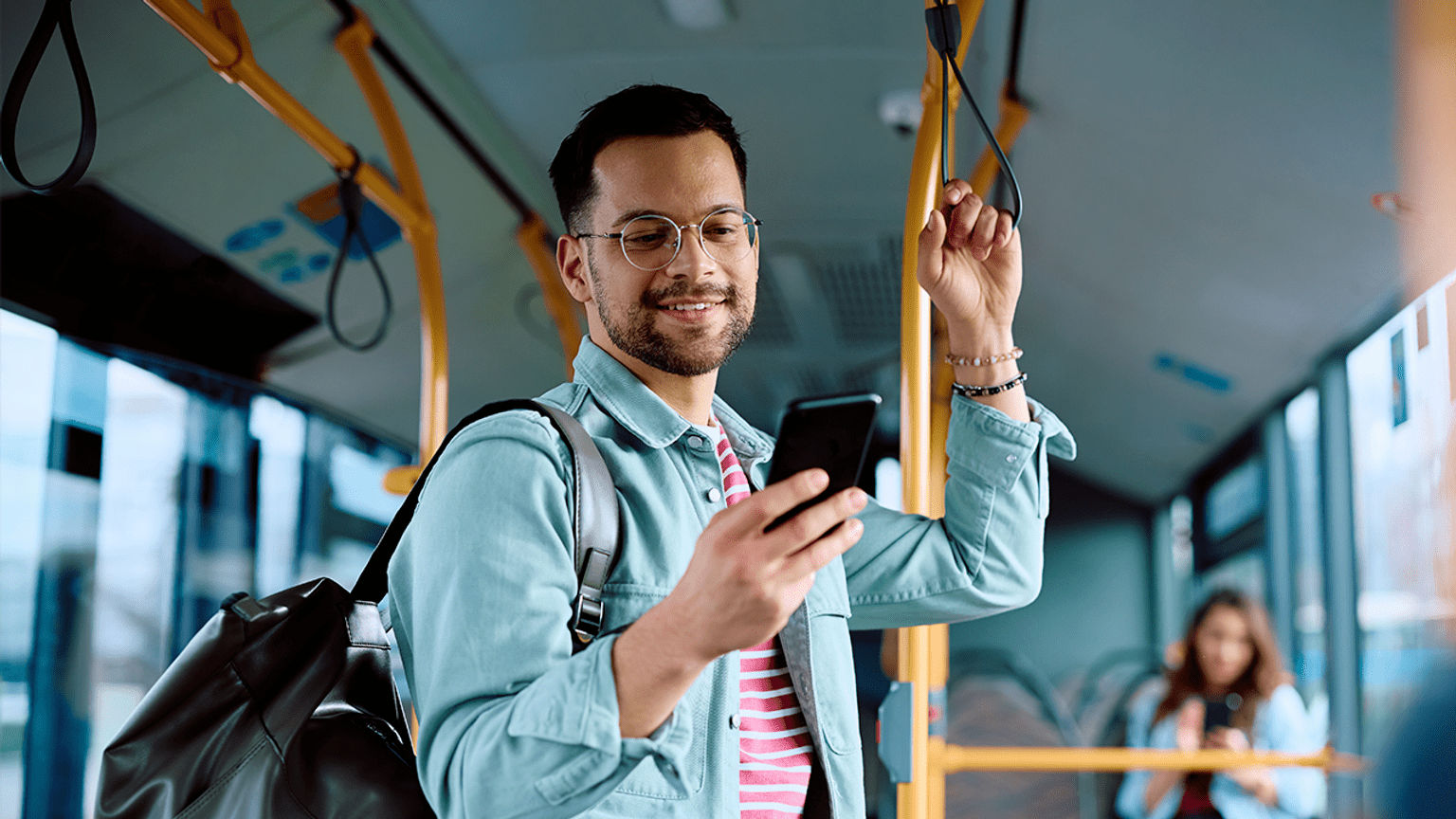 A person smiling holding a phone on a tram.