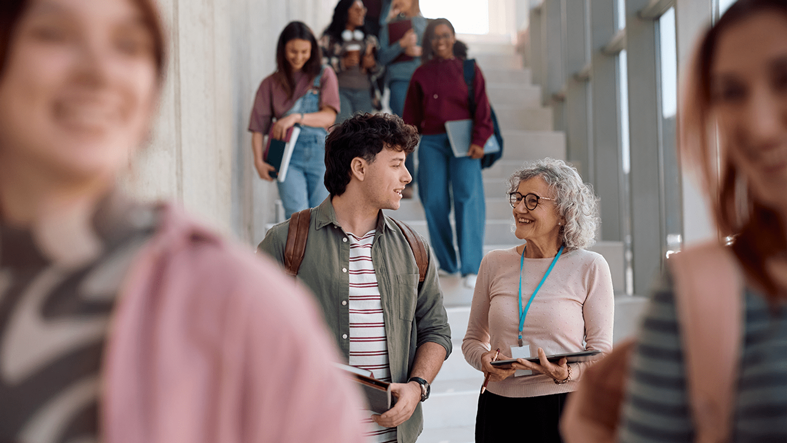 Two people in a stairwell smiling at each other. People are in front of them and behind them.