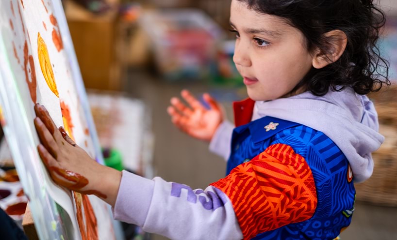 A child hand painting on a colouring paper on easel
