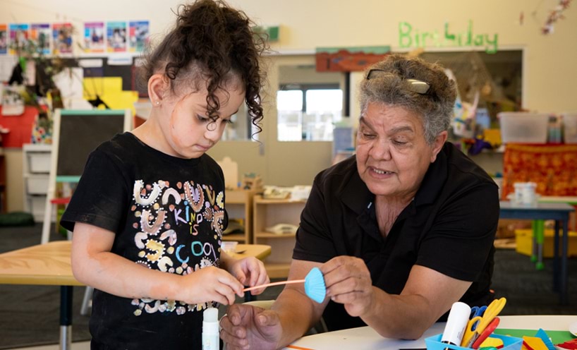 An educator helping a child with craft